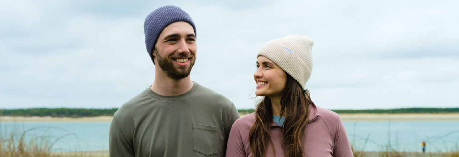 Man and woman standing by a beach in Free Fly travel clothing