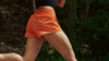 Person wearing orange shorts running in a forest