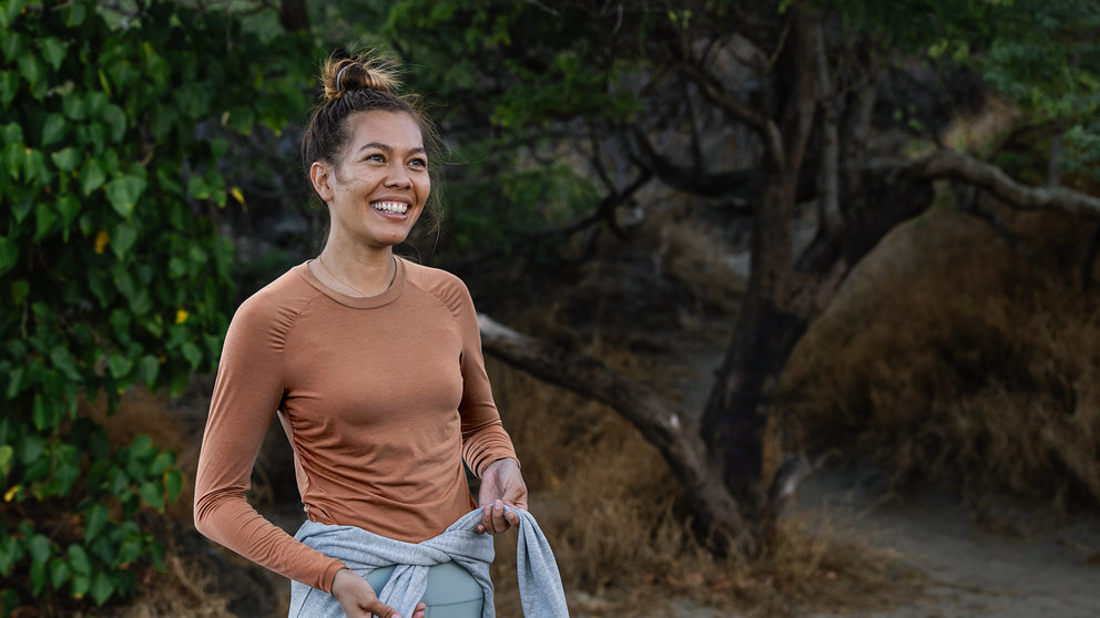 Woman standing outdoors with greenery in the background