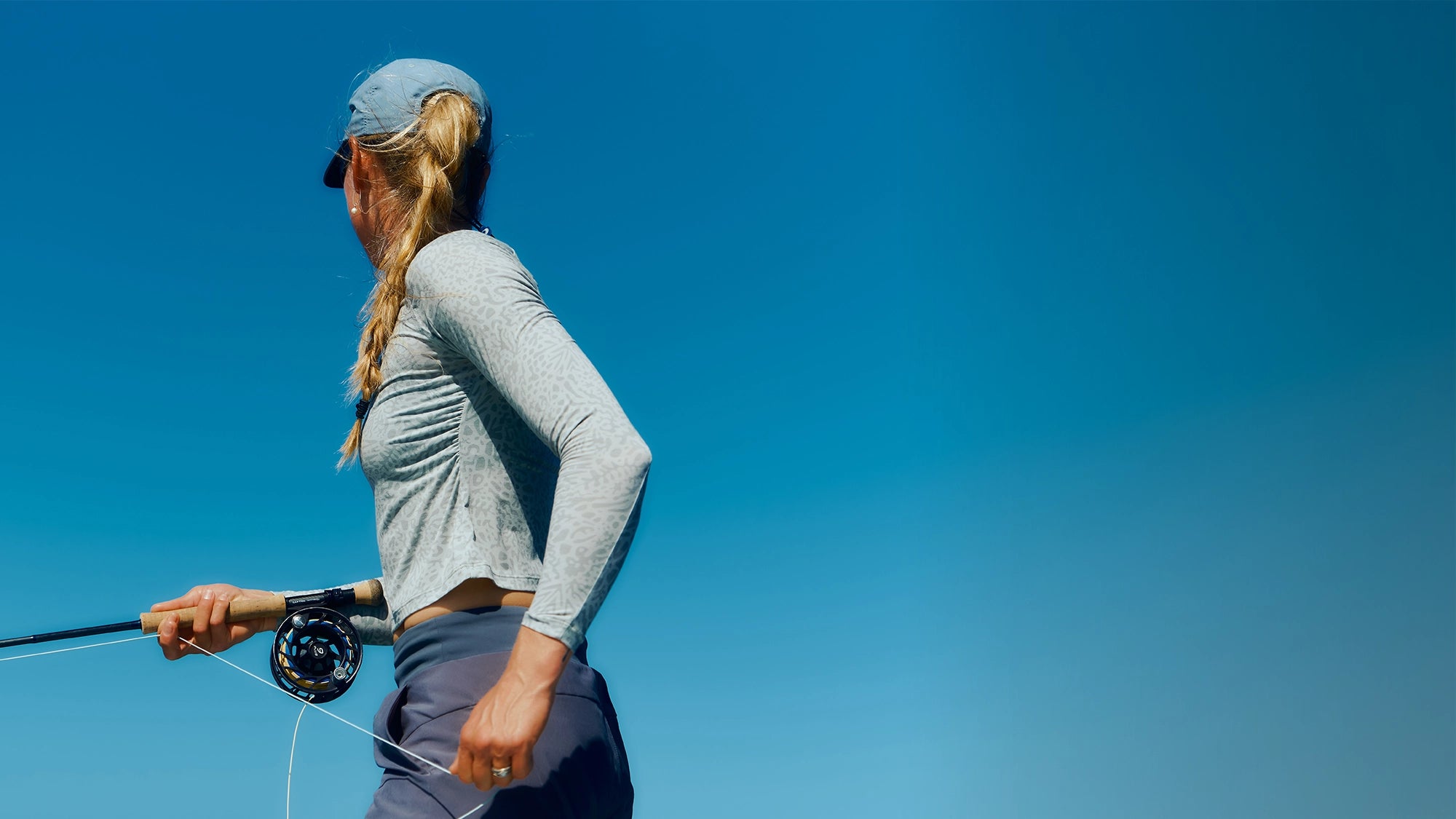 Woman fly fishing against a clear blue sky