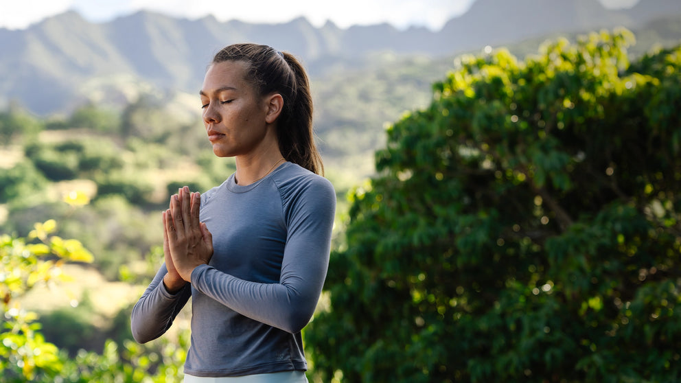 Woman meditating with mountains and greenery in the background
