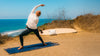 Person practicing yoga on a beach with ocean view