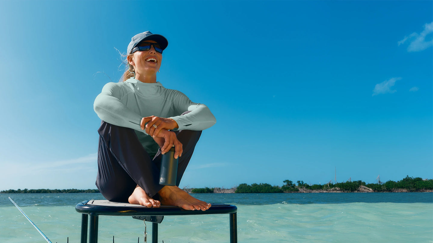 Person sitting on a stool in clear water with a blue sky background