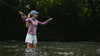 Person fly fishing in a river with a blurred natural background