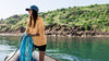 Woman on a boat holding blue ropes with a scenic background
