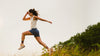 Woman jumping in a field with a clear sky