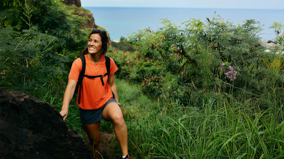 Person hiking through a lush green landscape with ocean view